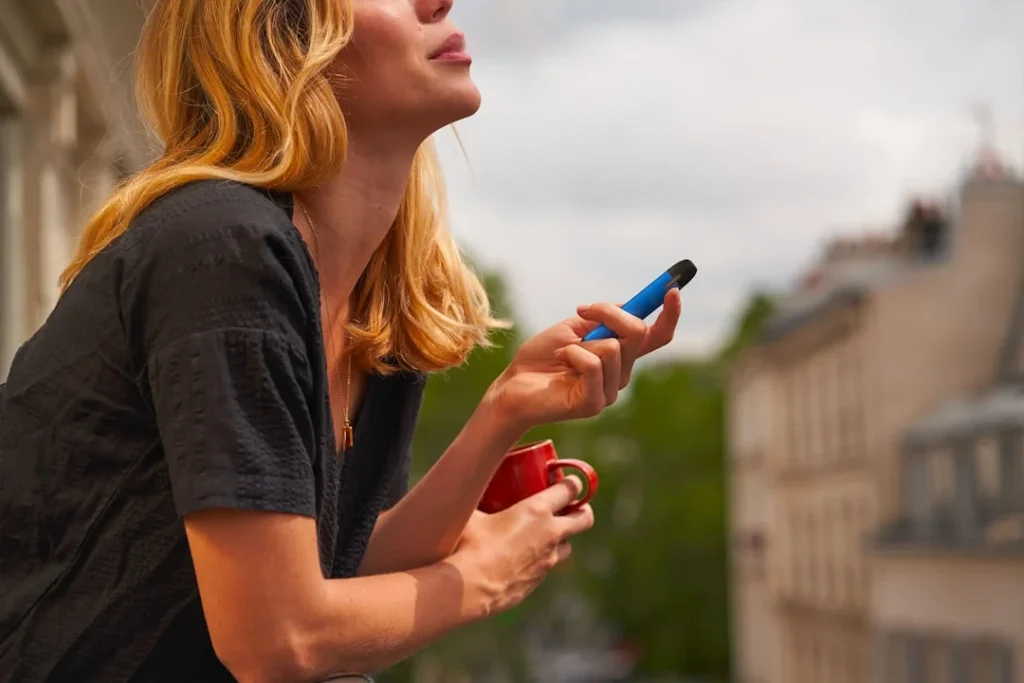 a-woman-holding-a-cup-and-a-cell-phone
